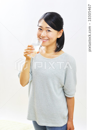 A woman drinking a glass of water 18305467