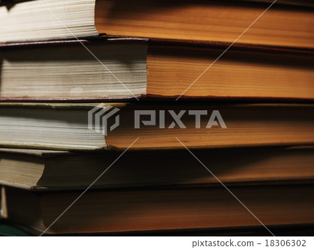 Pile of hardcover books in a shadowy room 18306302