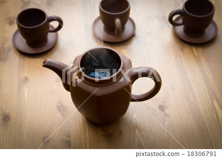 Clay teapot and cups on a wooden table 18306791