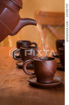 Clay teapot and cups on a wooden table 18306795