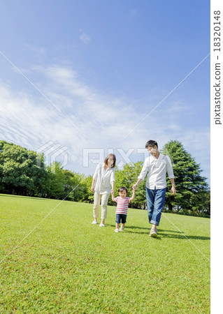 Three families walking hand in hand across the park 18320148