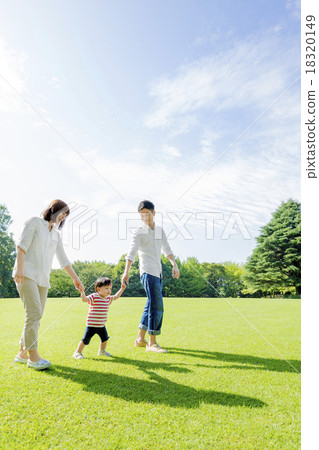 Three families walking hand in hand across the park 18320149