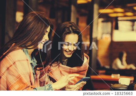 Two girl sitting listening to music Two girl sitting listening to music 18325663