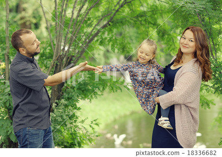 Mom and young daughter and dad, a young family on a walk in the park in summer 18336682