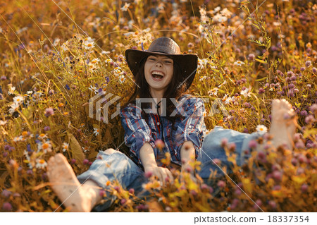 Happy American woman in a cowboy hat field wild flowers Happy American woman in a cowboy hat field wild flowers 18337354