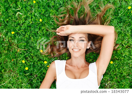 young woman in white dress lying on grass young woman in white dress lying on grass 18343077