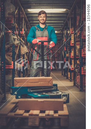 Loader using hand pallet truck in a warehouse 18344096