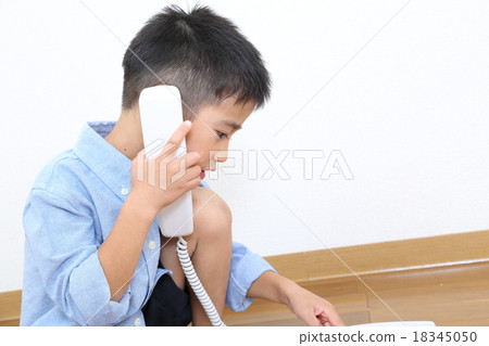 一個男孩用固定電話聽筒 一個男孩用固定電話聽筒 18345050