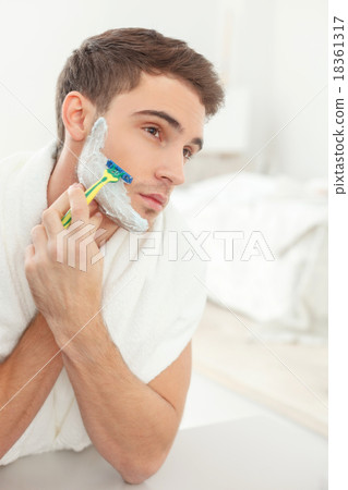 Attractive guy shaves with joy in bathroom Attractive guy shaves with joy in bathroom 18361317
