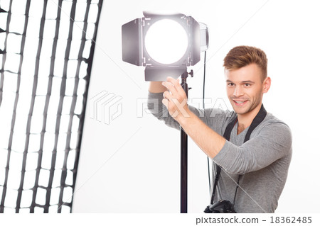 Smiling photographer is busy fixing the spotlight. 18362485