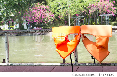 Orange life jackets dried on fence Orange life jackets dried on fence 18363430