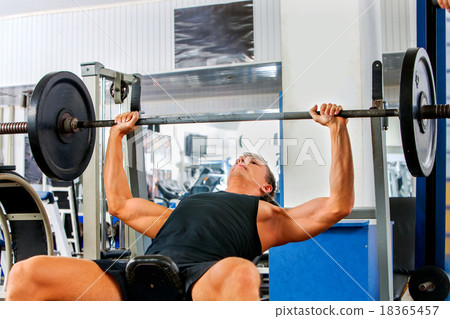 Man working his arms and chest at gym.  18365457