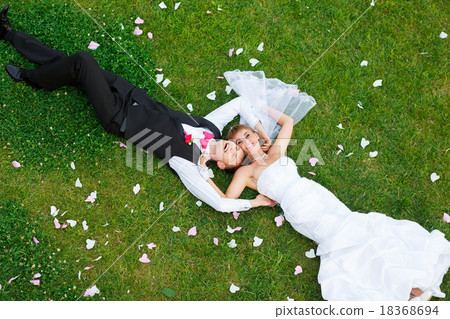 Happy wedding couple lying on green grass 18368694