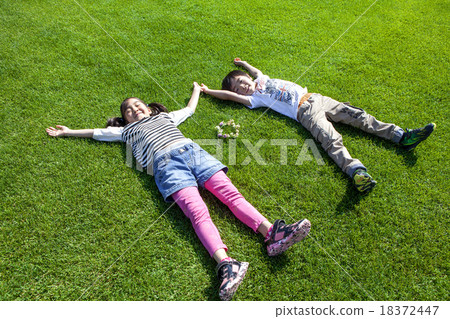 Boys and girls lying on the lawn in a large letter Boys and girls lying on the lawn in a large letter 18372447