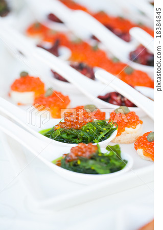 red caviar close-up in white spoons on banquet 18384845