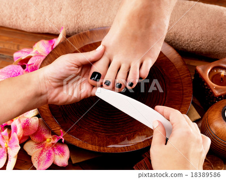Pedicurist master makes pedicure on woman's legs Pedicurist master makes pedicure on woman's legs 18389586