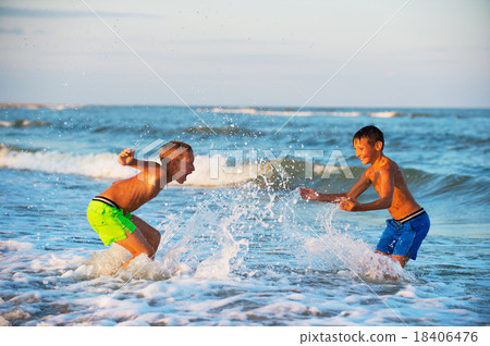 Two boys playing at the beach with water. Big splashes Two boys playing at the beach with water. Big splashes 18406476
