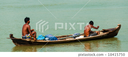 Two Asian men rowing wooden boat on a river 18415750