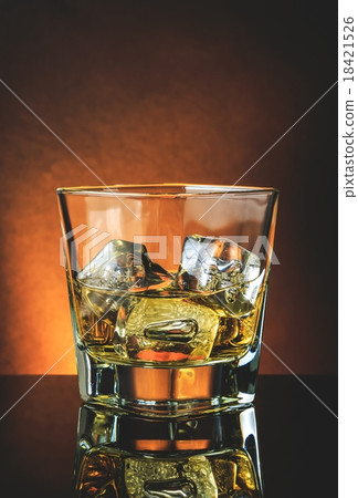 glass of whiskey on black table with reflection, warm atmosphere 18421526