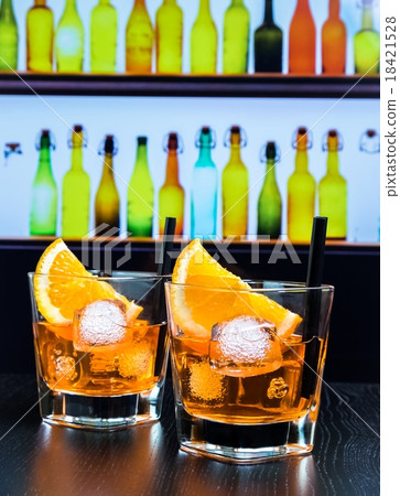 two glasses of spritz aperitif aperol cocktail with orange slices and ice cubes on bar table, disco atmosphere background two glasses of spritz aperitif aperol cocktail with orange slices and ice cubes on bar table, disco atmosphere background 18421528