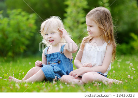 Two sisters sitting on the grass on summer day 18430328
