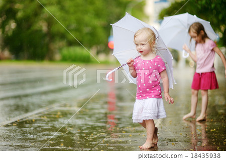 Two cute little sisters having fun under a rain Two cute little sisters having fun under a rain 18435938