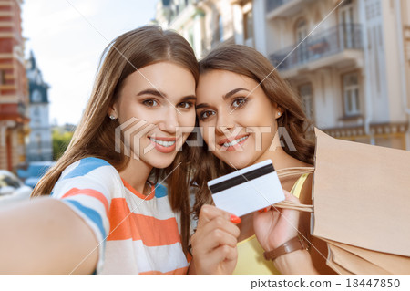 Two friends doing selfie with shopping bags Two friends doing selfie with shopping bags 18447850