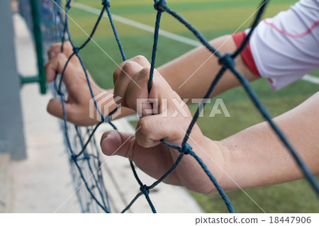 Hand holding soccer net beside a football stadium 18447906