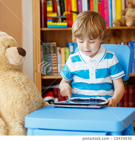 Little kid boy playing with tablet computer in his room at home 18459830