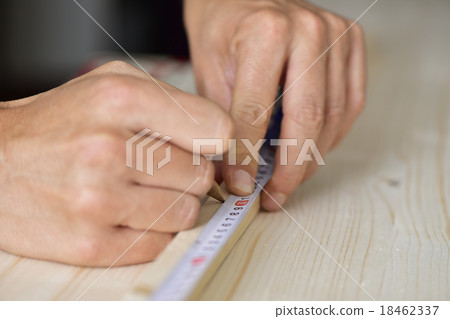 young man taking measurements in a wooden board young man taking measurements in a wooden board 18462337