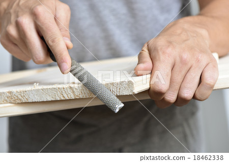 young man filing a wooden board with a rasp 18462338
