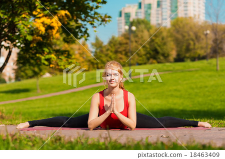 Young girl is engaged in yoga, outdoors in a park 18463409