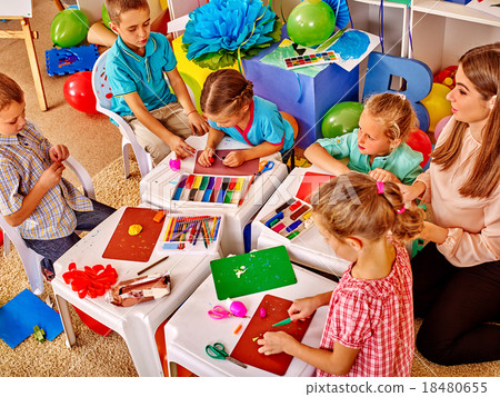 Kids holding colored paper and glue on table in Kids holding colored paper and glue on table in 18480655