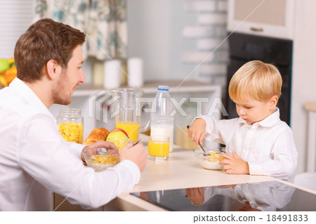 Father watches his son eating cornflakes. Father watches his son eating cornflakes. 18491833