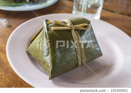 The rice wrapped in banana leaf on the wooden table The rice wrapped in banana leaf on the wooden table 18500091
