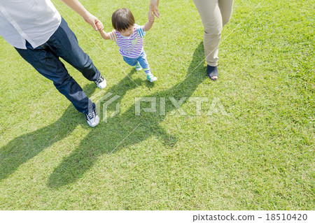 Three families walking hand in hand across the park 18510420