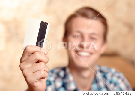 Smiling man showing his credit card Smiling man showing his credit card 18545432