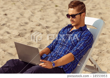 Handsome freelancer lying on the beach  18553953