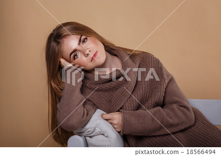 Girl in a warm sweater leaning on the arm of sofa. 18566494