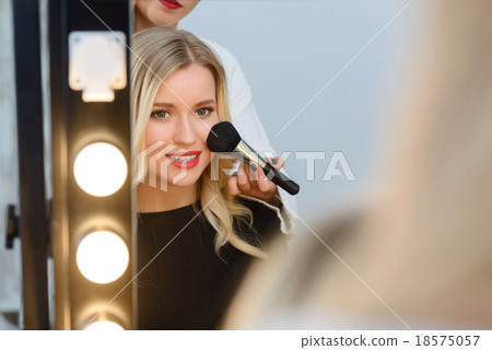 Model sitting in front of mirror while applying 18575057
