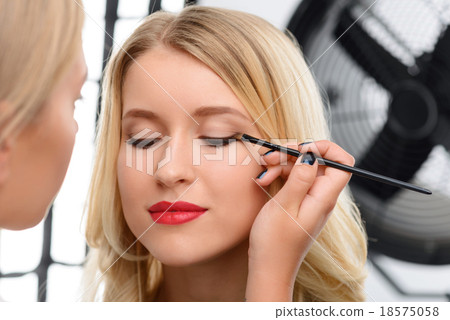 Stock Photo: Makeup artist working with models eye makeup.