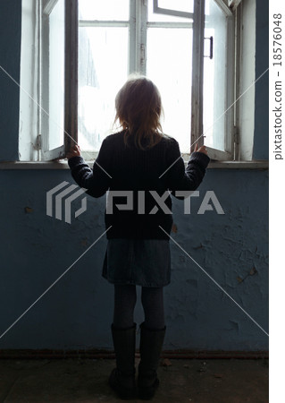 Depressed poot girl standing near window  18576048