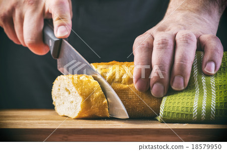 Man's hands cutting bread on the wooden plank 18579950