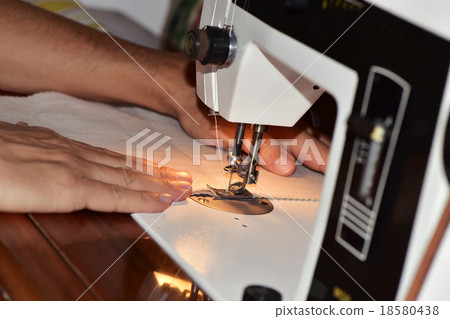 young man using a sewing machine young man using a sewing machine 18580438