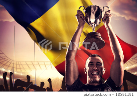 Composite image of portrait of successful rugby player holding t 18591191