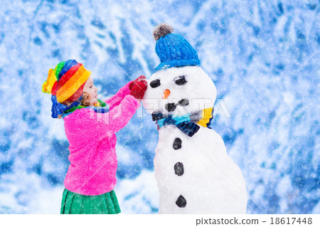 Little girl building a snow man in winter Little girl building a snow man in winter 18617448