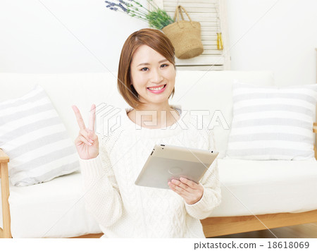 Female peace sign using tablet in room Female peace sign using tablet in room 18618069