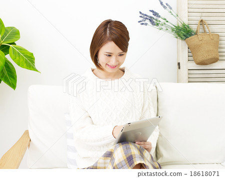 A woman who uses a tablet in a room A woman who uses a tablet in a room 18618071