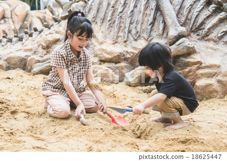 Little asian children has fun digging in the sand 18625447