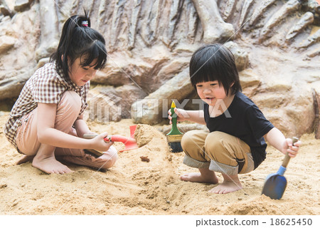 Little asian children has fun digging in the sand 18625450